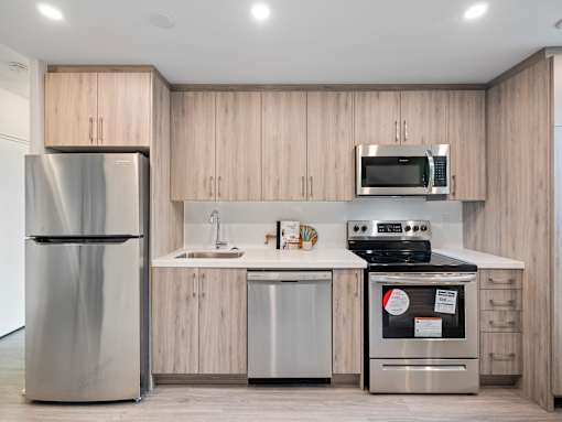 A modern kitchen with a refrigerator, microwave, oven, and sink.