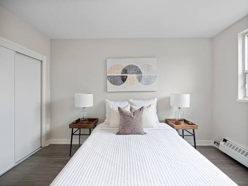 A bedroom with a large bed, two lamps, and a painting on the wall.