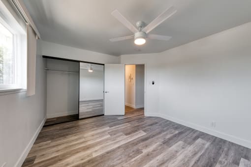 a bedroom with white walls and a ceiling fan