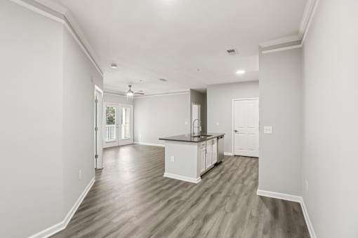 A spacious kitchen with white cabinets and a wooden floor.