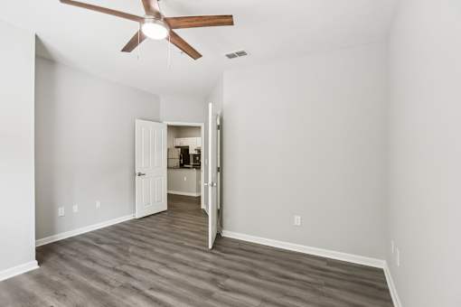 A room with a ceiling fan and a doorway leading to another room.