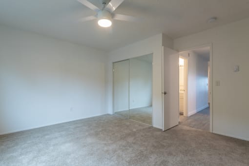 a bedroom with white walls and a ceiling fan