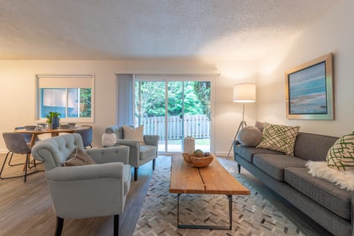 a living room with couches chairs and a coffee table in front of a sliding glass door
