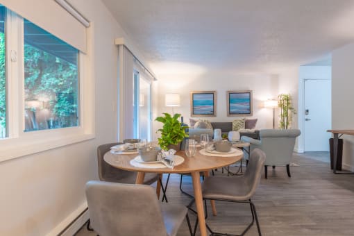 a dining area with a table and chairs and a living room in the background