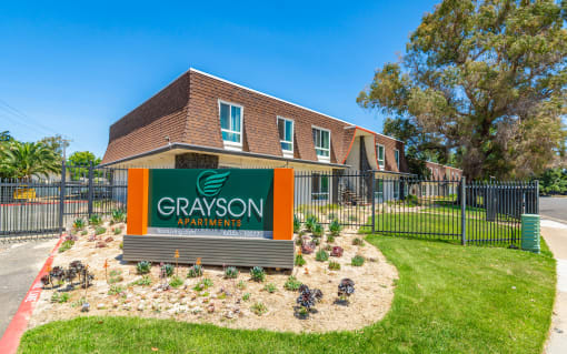 a green and orange sign in front of a brick building