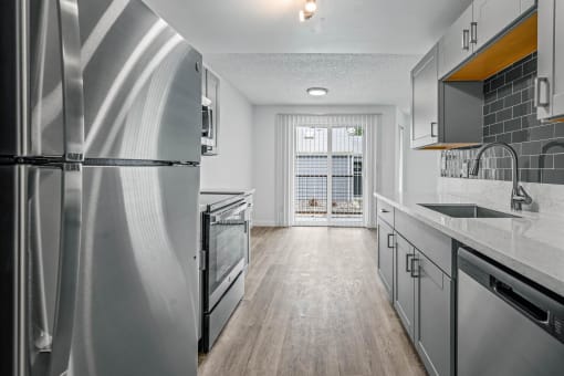 a kitchen with gray cabinets and stainless steel appliances