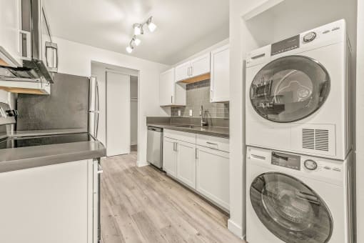 a kitchen with white cabinetry and a washer and dryer