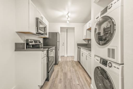 a kitchen with white cabinetry and a washer and dryer
