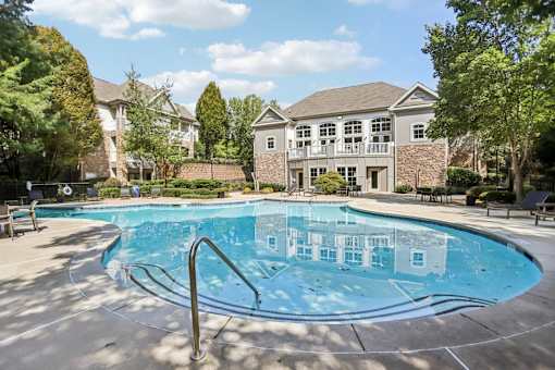 A swimming pool in front of a house with a brick wall.