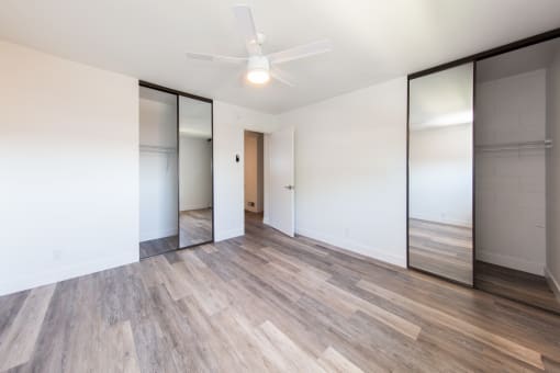 a bedroom with white walls and a ceiling fan