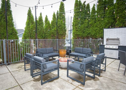 the patio has a gas grill and chairs around a fire pit