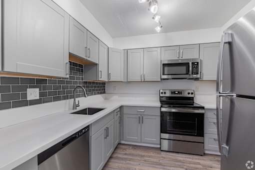 A kitchen with a stainless steel refrigerator, oven, and microwave.