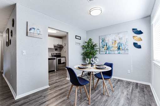 a dining area with a table and chairs and a kitchen in the background