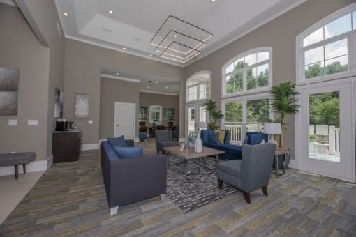 a living room with couches and chairs and large windows