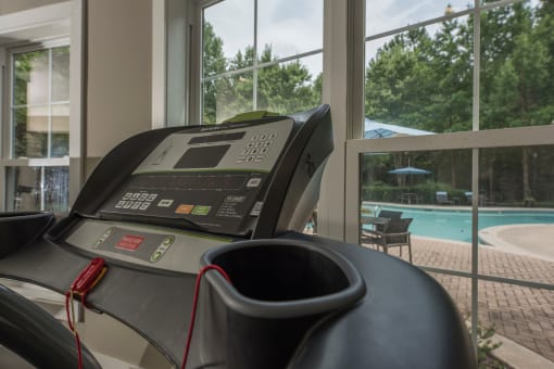 a treadmill in a gym with a pool in the background