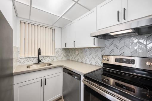 a kitchen with white cabinets and black appliances and a sink