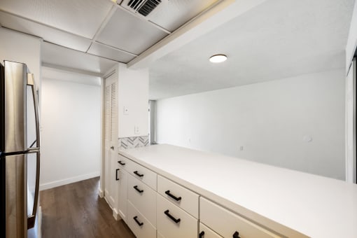an empty kitchen with white cabinets and a stainless steel refrigerator
