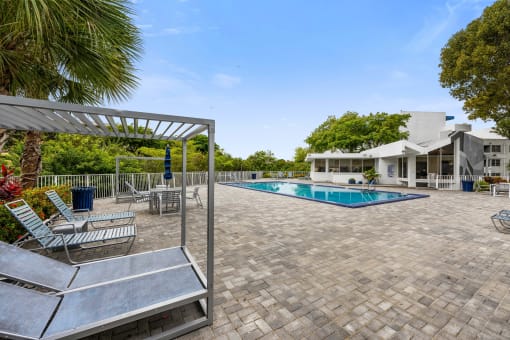 a swimming pool with chairs and a house in the background