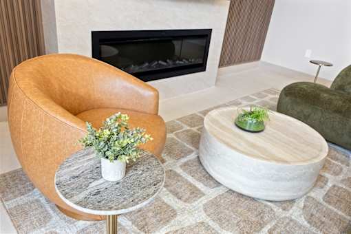 A brown leather chair sits in front of a fireplace with a small potted plant on a table.