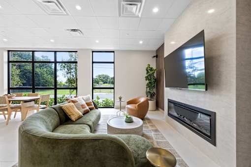 A modern living room with a green couch and a flat screen TV mounted on the wall.