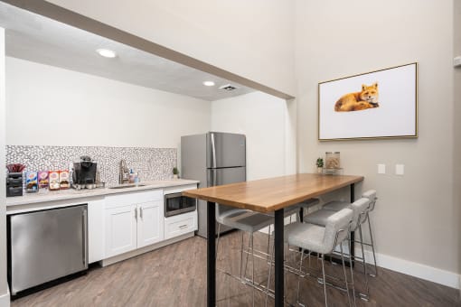 a kitchen with white cabinets and a wooden table with three stools