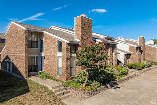 A row of brick apartment buildings with a tree in front.
