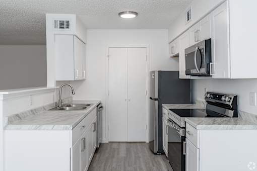 A kitchen with white cabinets and black appliances.