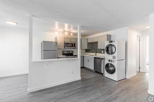 A kitchen with white appliances and a grey floor.