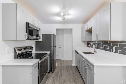 A kitchen with white cabinets and black appliances.