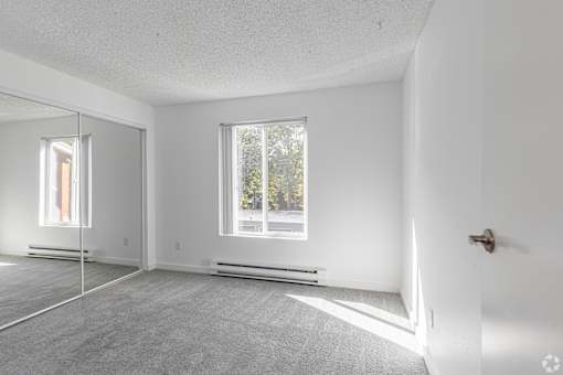 A white room with a door, window, and a mirror.