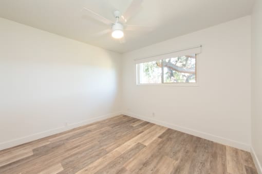 an empty room with a ceiling fan and a window