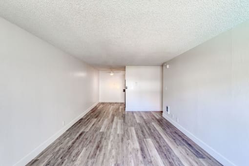 a spacious living room with hardwood floors and white walls