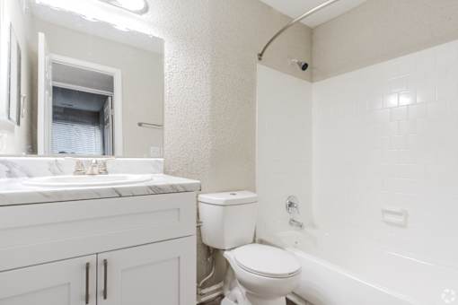 A white bathroom with a toilet, sink, and bathtub.