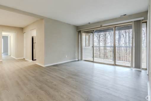 A spacious room with a sliding glass door leading to a balcony.
