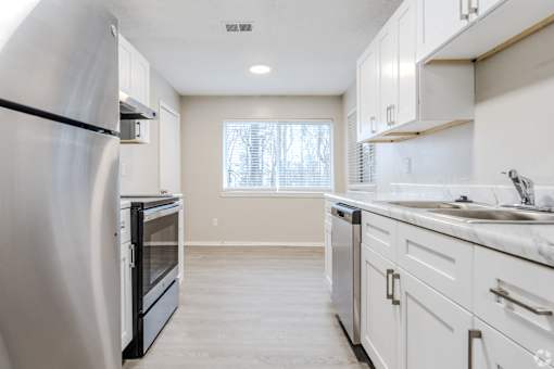 A kitchen with white cabinets and a black fridge.