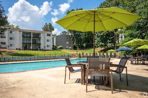 A yellow umbrella is in the foreground of a pool area.