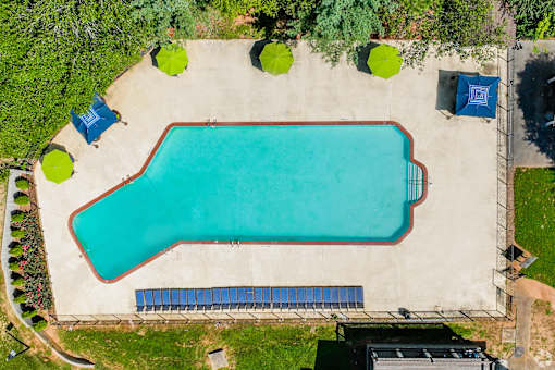 A rectangular pool surrounded by a concrete floor and a metal fence.