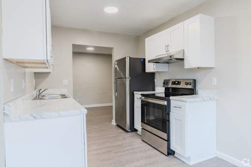 A kitchen with white cabinets and a black refrigerator.