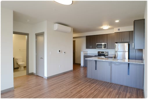 a kitchen with an island and a toilet in the background