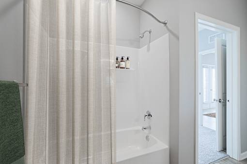 A white bathroom with a green towel hanging on the side.