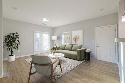 A living room with a green couch, a chair, and a potted plant.