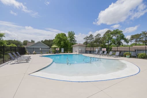 our apartments have an outdoor pool with chairs and trees