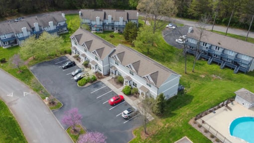 an aerial view of three buildings with cars parked in front of them