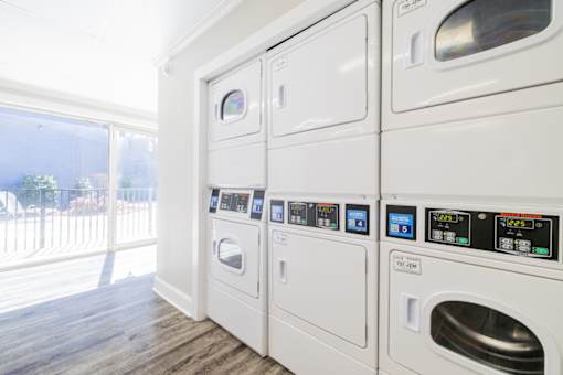 A row of white front loading washing machines in a laundry room.