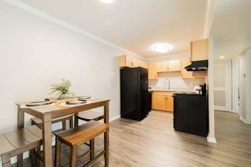 A kitchen with a black refrigerator and wooden furniture.