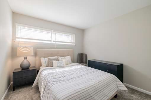 A bedroom with a bed, nightstand, and window.