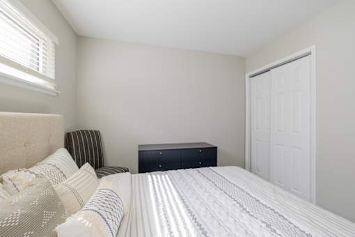 A bedroom with a bed, pillows, and a nightstand.