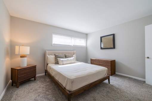A bedroom with a bed, nightstand, and lamp.