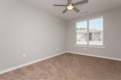 A room with a ceiling fan and carpeted floor.