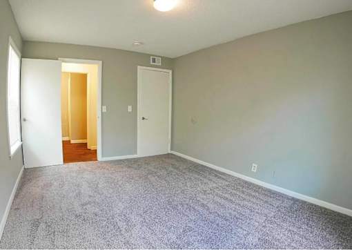 A room with a carpeted floor and two doors.